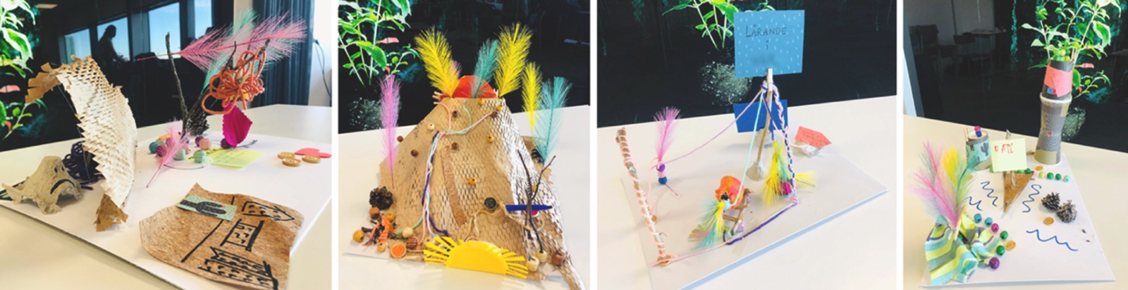 Four small physical models on white tables, built from textiles, cardboard, feathers, buttons and pipe cleaners, each one representing a group’s story of the future