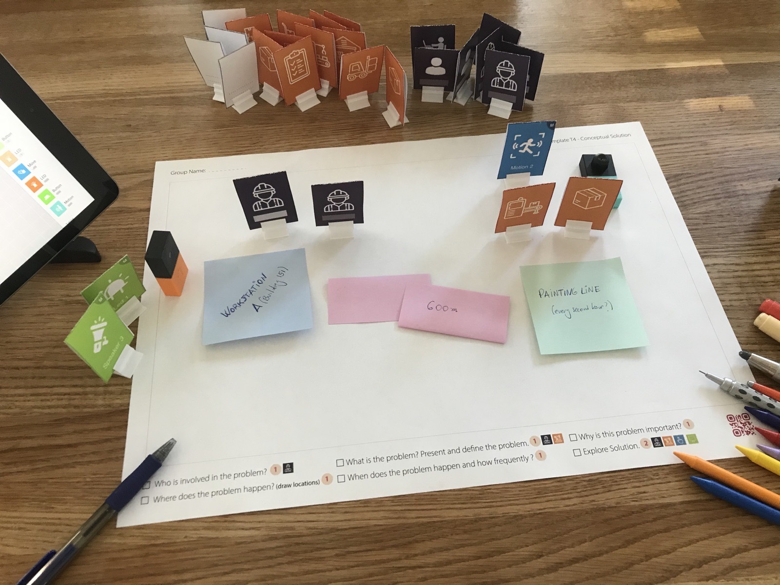 Close-up of the canvas with two worker tokens, sticky notes reading Workstation A, 600 m and Painting line, a motion sensor token, a box token, a speaker token and two small sensor blocks